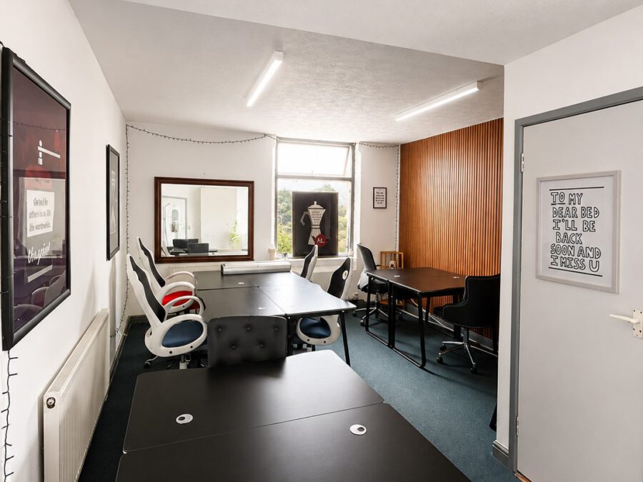 The main coworking room at Coworking Beeston, with rows of desks, a wooden slat wall and a window at the far end