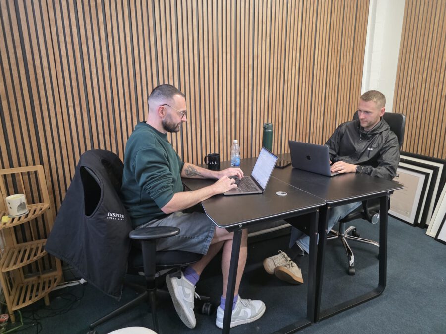 Two members working side by side on laptops at a shared desk